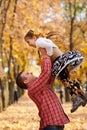 Father throws the daughter high up in autumn city park. They posing, smiling, playing. Bright yellow trees. Royalty Free Stock Photo
