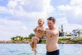 Father throws a little son in the air above the water in the sea