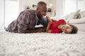 Father Tickling Son As They Play Game In Lounge Together