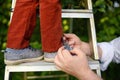 Father tie a lace on the shoe his little son. Child standing on ladder near tree in domestic garden