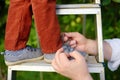 Father tie a lace on the shoe his little son. Child standing on ladder near tree in domestic garden