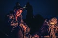 Father and son sitting by the campfire in outdoors camp in the night after long hunting day