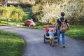 A father with toddler son pushing a jogging stroller outside in spring nature.