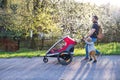 A father with toddler son pushing a jogging stroller outside in spring nature. Royalty Free Stock Photo