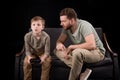 Father trying to talk with little son playing with joystick