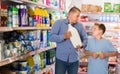 Father and tween son choosing household chemicals in supermarket Royalty Free Stock Photo