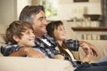 Father And Two Children Sitting On Sofa At Home Watching TV Together Royalty Free Stock Photo