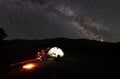 Father and two children hikers having a rest at camping in mountains under night sky full of stars and Milky way Royalty Free Stock Photo