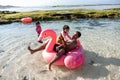 Father and two daughters ride flamingo buoy on the beach Royalty Free Stock Photo