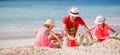 Father and two girls playing with sand on tropical beach Royalty Free Stock Photo