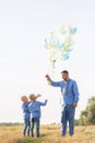 Father with two his twins sons play on meadow with air balloons Royalty Free Stock Photo