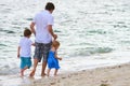 Father with two kids walking along beach Royalty Free Stock Photo