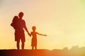 Father and two kids walking on beach at sunset