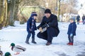 Father and two little siblings boys feeding ducks in winter. Royalty Free Stock Photo