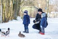 Father and two little siblings boys feeding ducks in winter. Royalty Free Stock Photo