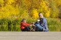 Father and two sons play on the pier. Autumn, sunny. Side view Royalty Free Stock Photo