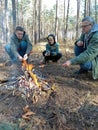 A father and two sons are sitting by the fire and roasting sausages on skewers Royalty Free Stock Photo