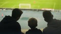 Father and two sons watching football match together, happy weekend, fatherhood