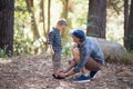 Father tying shoelace of son in forest