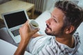 Father using laptop while having coffee in living room Royalty Free Stock Photo