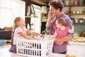 Father Using Mobile Phone As He Sorts Laundry With Children Royalty Free Stock Photo