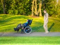 Father walking with disabled son in wheelchair at lake park Royalty Free Stock Photo