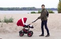 The father walks with baby in the baby carriage in the park