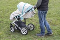 Father walks with carriage, bottom view only legs. Bright mint stroller and legs in jeans, walking with a child outdoor