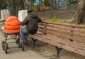 Father walks with his child in the pram, sitting on a bench in the Park