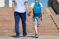 the father walks with his son up the stairs to the school