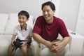 Father watching son play video game on couch