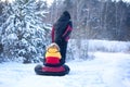 Father in winter clothes pulling sledges with his son in winter snowy forest. Happy family walk in snowy forest