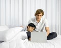 Father work at home with son. A boy napping on his father`s lap while the father using laptop computer to work in the bedroom. Royalty Free Stock Photo