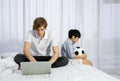 Father work at home with son.  Young caucasian father using laptop computer to work in the bedroom while his adopted son waiting Royalty Free Stock Photo