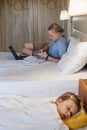 Father working while child is slipping on the bed in hotel Royalty Free Stock Photo