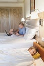 Father working while child is slipping on the bed in hotel Royalty Free Stock Photo