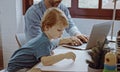 Father working from home office using laptop sit at table with cute little son playing nearly to disturb Royalty Free Stock Photo