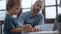 Father working from home office using laptop sit at table with cute little son playing nearly to disturb Royalty Free Stock Photo