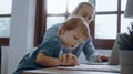 Father working from home office using laptop sit at table with cute little son playing nearly to disturb Royalty Free Stock Photo