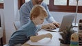 Father working from home office using laptop sit at table with cute little son playing nearly to disturb Royalty Free Stock Photo