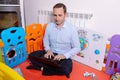 Father working with laptop inside baby playground to take care of his son