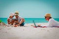 Father working on laptop while kids looking at touch pad at beach Royalty Free Stock Photo