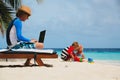 Father working on laptop while kids play at beach Royalty Free Stock Photo