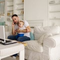 Father working, talking on phone and babysitting Royalty Free Stock Photo