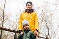 Father in yellow raincoat and son having fun in forest. Happy family with child kid boy playing and having fun outdoors Royalty Free Stock Photo