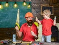 Fatherhood concept. Boy, child cheerful playing and learning to use tools with dad. Father, parent with beard in