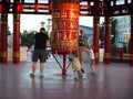 Fathers with children of different nationalities walk around the red prayer Buddhist drum wheels. Russia, Elista - June