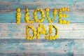 Fathers day background with letters from yellow dandelions on old turquoise wooden background. Copy space. Royalty Free Stock Photo