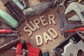 Fathers day concept. Set of old tools on a wooden carpenter desk with Super Dad text. Happy holiday. Royalty Free Stock Photo