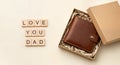 Wallet gift in box with wooden tiles spelling love you dad on surface, fathers day Royalty Free Stock Photo